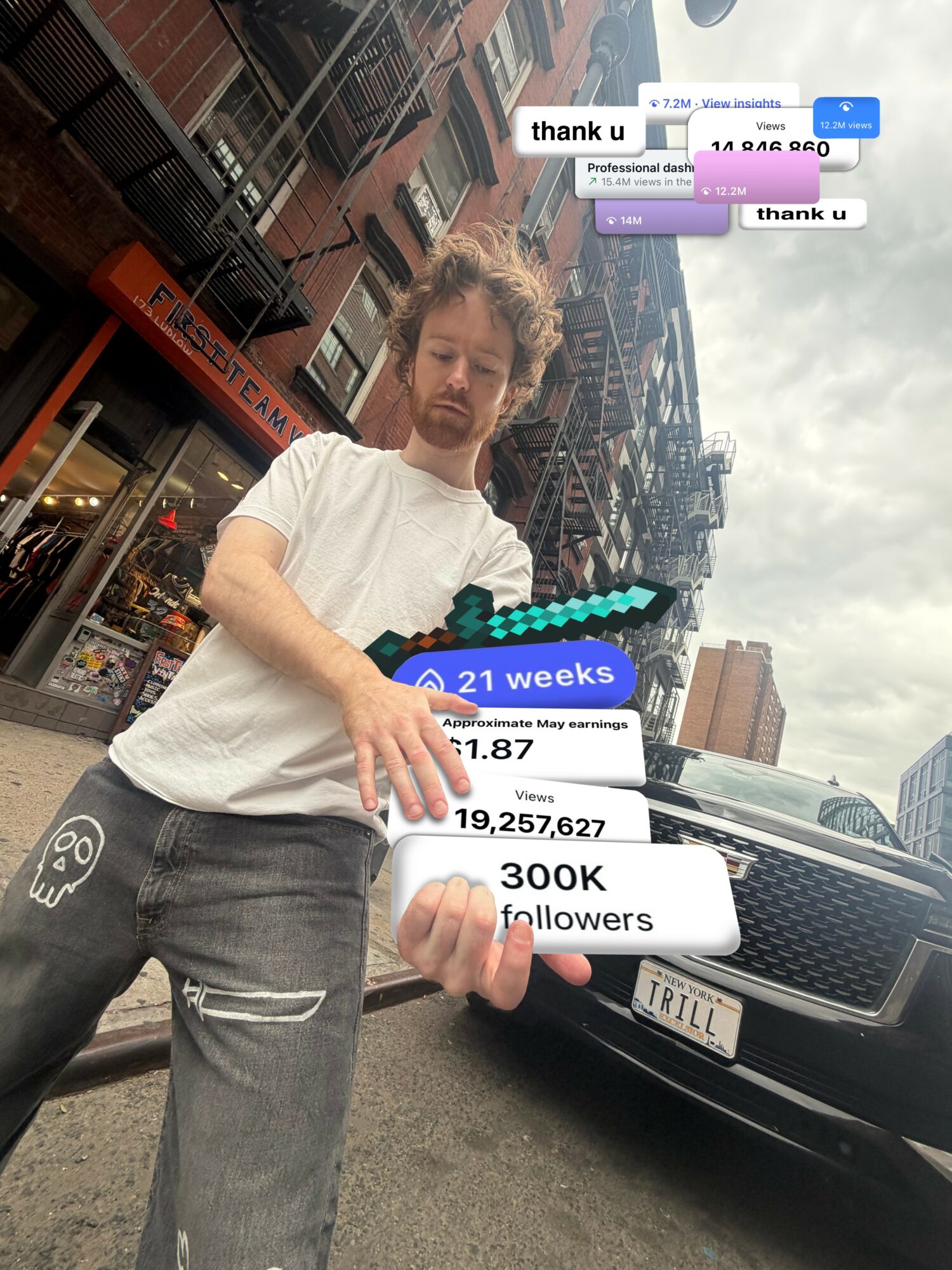 Young man standing on city street holding a phone, with buildings and cars in background.