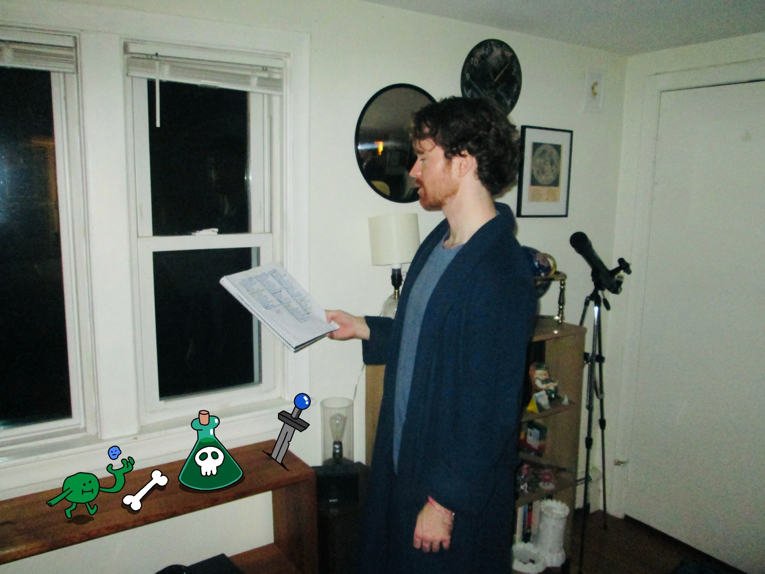 Young man with glasses reading sheet music in a room with a window, microphone, and decorative items on the wall.