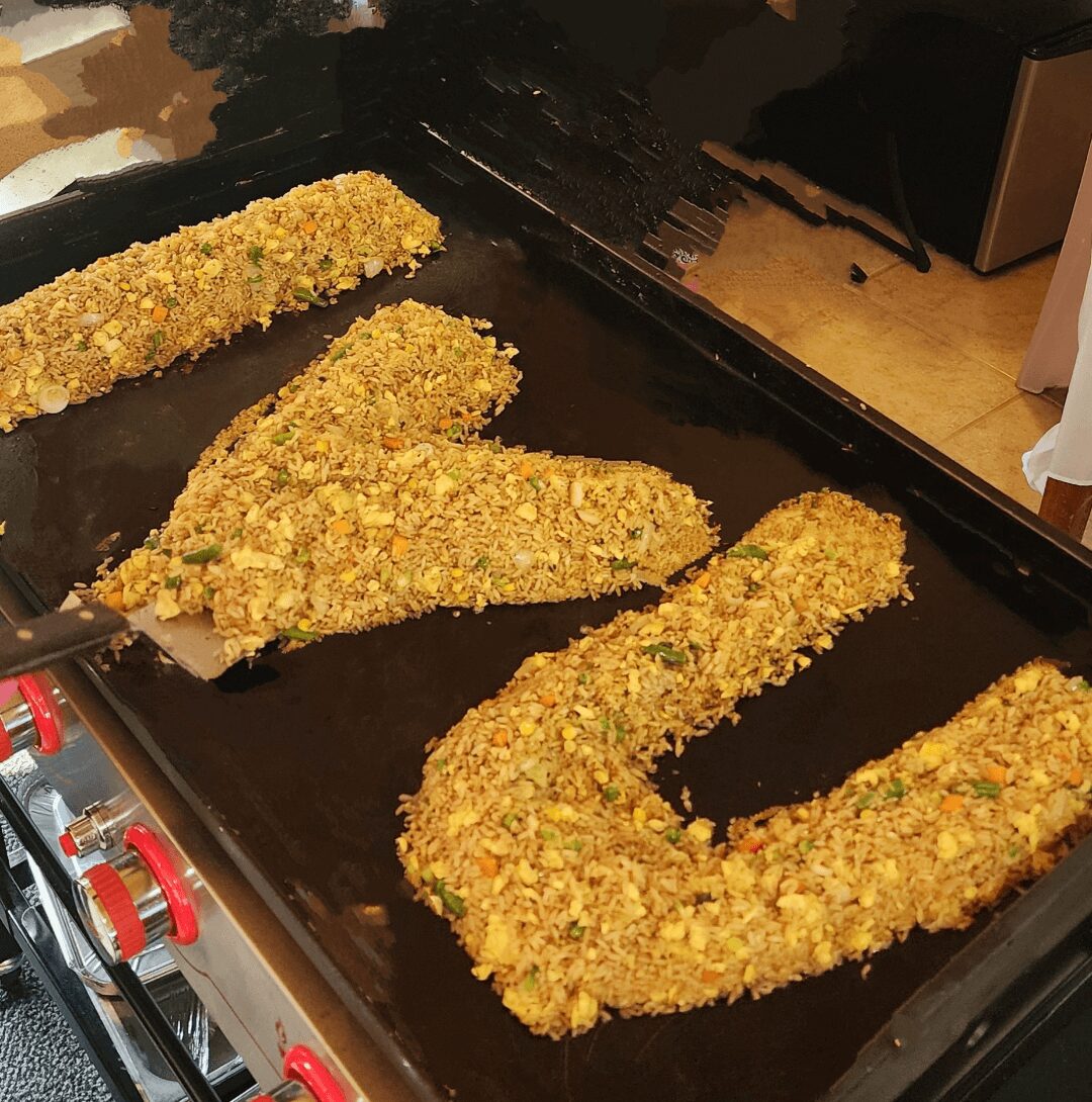 Four breaded, fried food pieces on a black tray, with one shaped like a U. The tray is on a countertop.