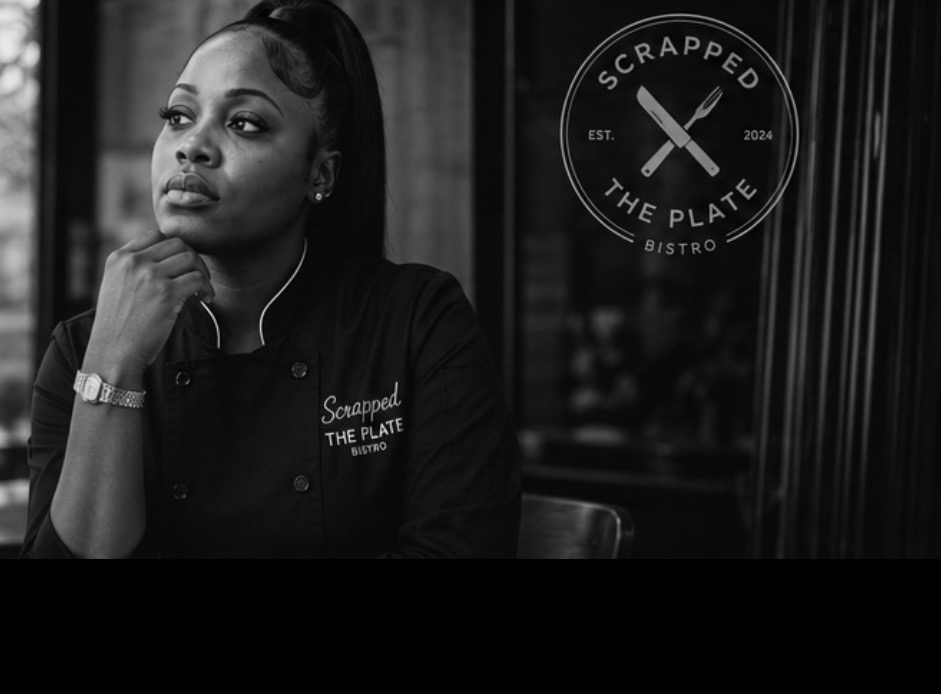 Woman in chef's uniform sitting in front of a sign for Scrapped The Plate Bistro, looking thoughtful.