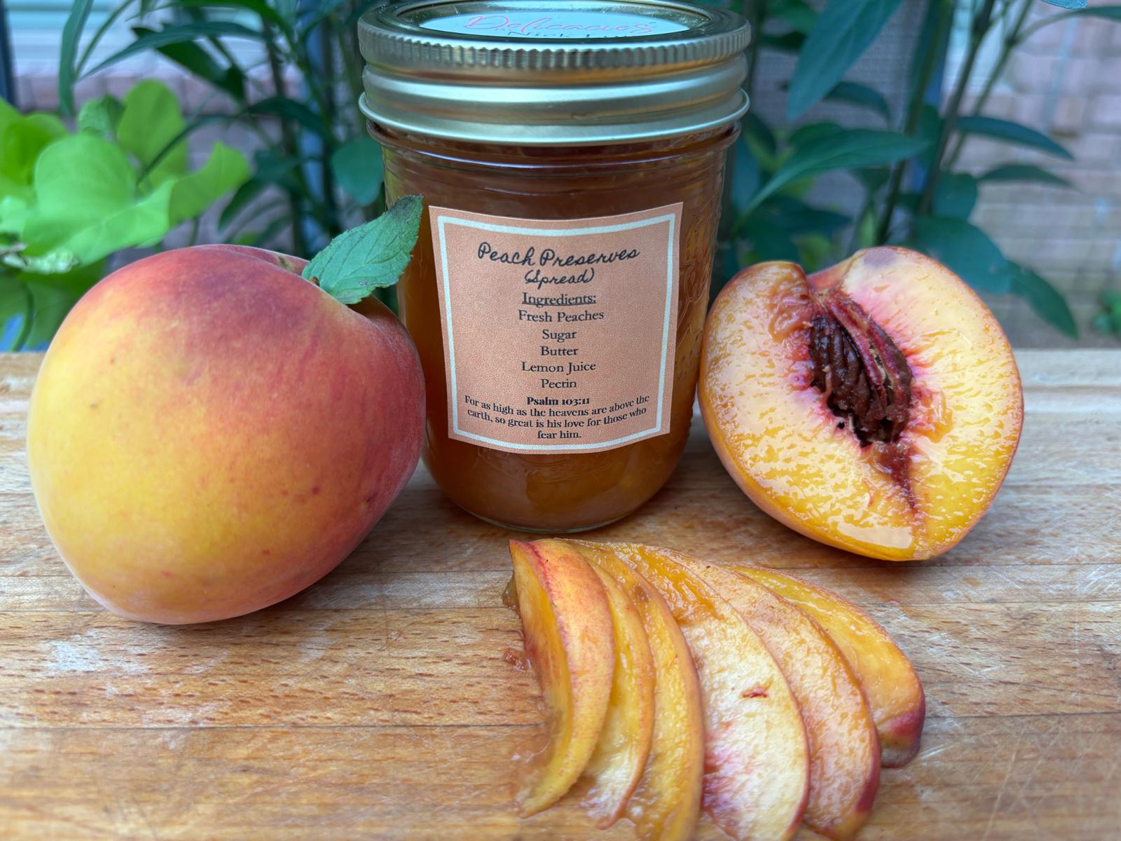 Peach, peach slices, and a jar of peach preserves on a wooden surface with green plants in background.